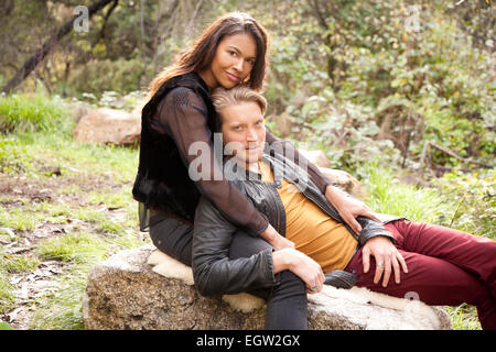 Man lying on woman's lap on rock. Stock Photo