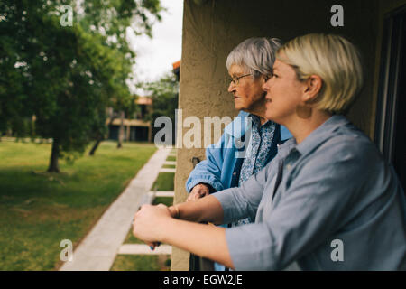 Senior woman and younger woman leaning on porch railing. Stock Photo