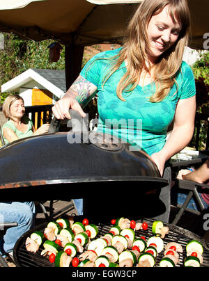 Woman lifting lid on grill. Stock Photo