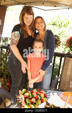 Two women and child in front of table with food.
