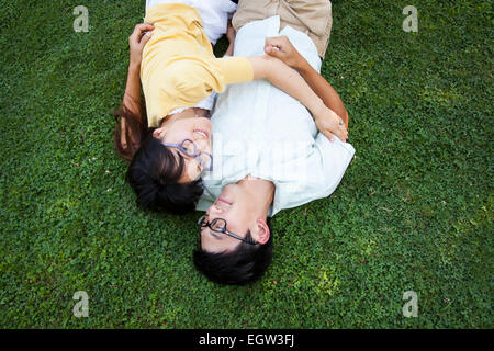 Couple embracing and lying in grass. Stock Photo