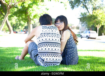 Couple sitting on grass together. Stock Photo