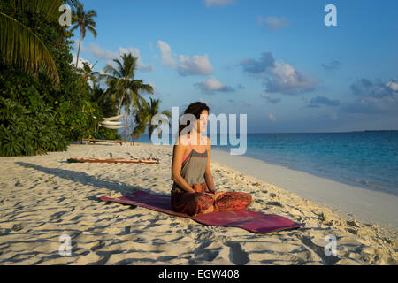 Woman meditating on beach in the Maldives. Stock Photo