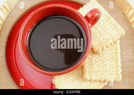 coffee served in a red cup with three biscuits Stock Photo