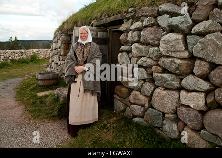 Gaelic woman standing outside Black House at The Highland Village Museum in Iona, Nova Scotia, Canada Stock Photo