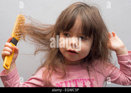 2-year old girl brushing her hair Stock Photo
