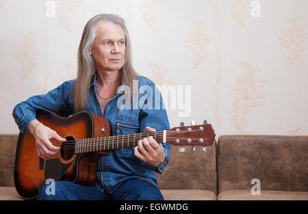 middle-aged man playing guitar at home Stock Photo