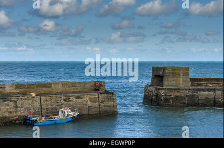 A small fishing boat moored in Craster Harbour harbor on a Spring day. Horizontal format with copyspace. Stock Photo