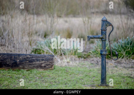 Old, hand-operated, positive displacement, reciprocating cast iron cast-iron water pump in a Yorkshire field. Stock Photo