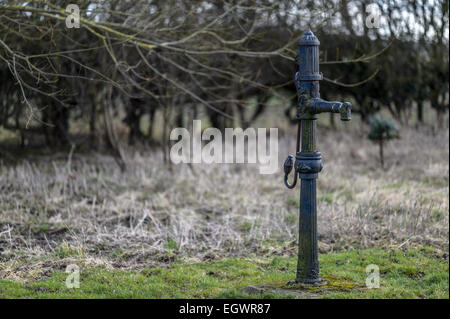 Old, hand-operated, reciprocating, positive displacement cast iron cast-iron water pump in a Yorkshire field. Stock Photo