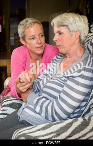 A daughter looking after her mother who is suffering from Alzeimer's. Stock Photo