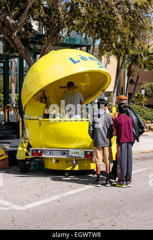 With people lining up to buy, this man is selling, from his lemon-shaped trailer, cold fresh lemonade in downtown Sarasota FL Stock Photo