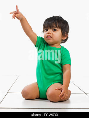 Baby boy (16 months) kneeling on floor and pointing his finger Stock Photo