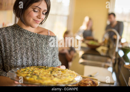 A woman carrying prepared food to the table. Stock Photo