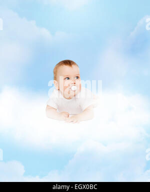 smiling baby lying on cloud with dummy in mouth Stock Photo