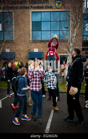 Local children do a rugby line out with players from London Welsh Rugby team at the Kassam Stadium Stock Photo