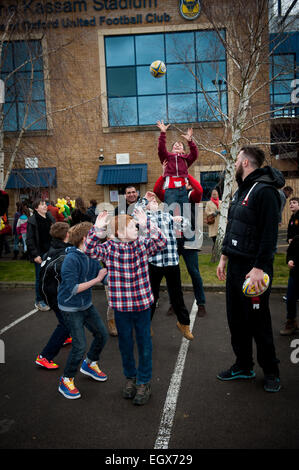Local children do a rugby line out with players from London Welsh Rugby team at the Kssam Stadium Stock Photo