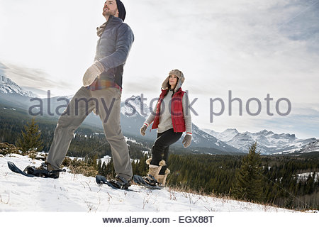 Couple snowshoeing below snowy mountains
