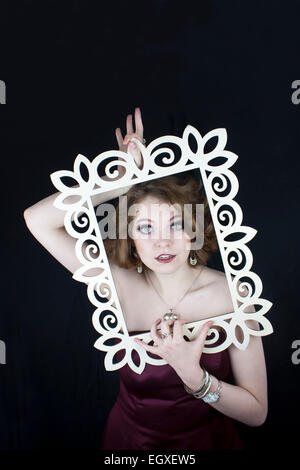 Beautiful woman holding white wooden frame with red roses Stock Photo