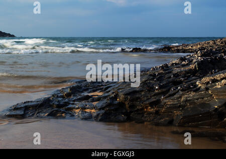 Waves crashing over limpet covered rocks on a bright sunny day, in Harlyn Bay, Cornwall, South West England, UK Stock Photo
