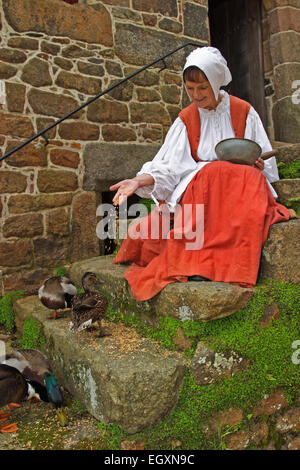 Lady dressed in period costume and feeding ducks / Hamptonne Country Life Museum / Jersey / UK Stock Photo