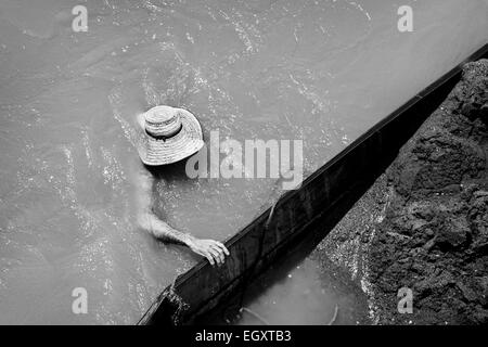 A Colombian sand miner dives under the water to extract sand from the bottom of the river in Cartago, Colombia. Stock Photo