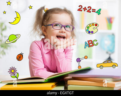 Funny smart kid in glasses reading book in kindergarten Stock Photo