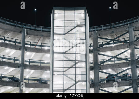 Cars parked in illuminated parking garage concrete structure at night Stock Photo