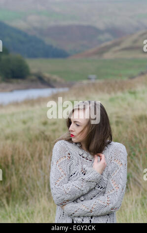 Beautiful young woman standing in the countryside looking away Stock Photo