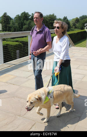 Woman with visual impairments with helper and guide dog in grounds of the Yorkshire Sculpture Park. Stock Photo