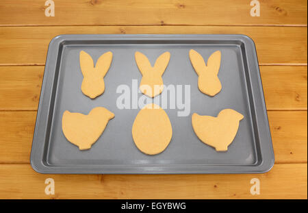 Cookie tray of Easter biscuits in rabbit, chick and egg shapes on a wooden table Stock Photo