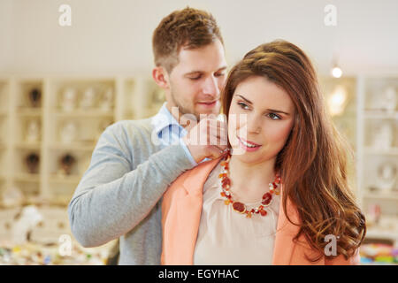 Salesman helping woman in jewelry store fitting a necklace Stock Photo