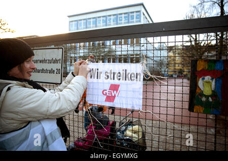 A protest sign hangs attached to a gate which reads 'We are on strike' at the Fleaming elementary school in Berlin, Germany, 2 March 2015. The teachers union 'Education and Science Workers' Union (Gewerkschaft Erziehung und Wissenschaft, GEW) is expecting around 1500 to 2000 of 6300 hired teacher in Berlin to lay down their work, as part of a warning strike for better pay. With the warning strikes, GEW wants to increase the pressure on the German states in the ongoing tariff conflict for hired teachers in civil services, demanding a 5.5 percent increase or at least 175 euros more pay overall Stock Photo