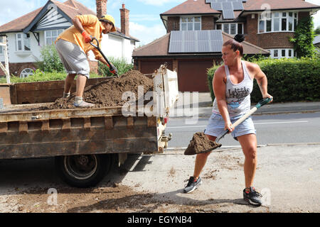 Women shovelling soil into lorry Stock Photo