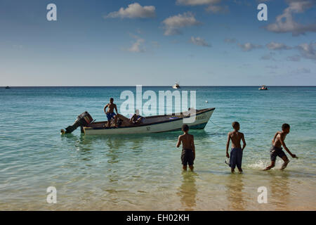 Barbados beach, fishing boat, boys in water Stock Photo