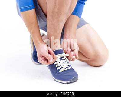 male athlete lacing up before exercise. Stock Photo