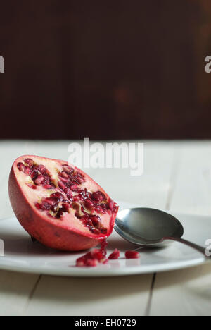 Still life food image of a Pomegranate on a white plate with spoon Stock Photo