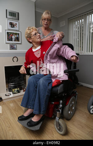 Carer putting Wheelchair user's coat - model released Stock Photo