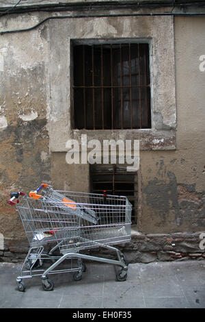 Old window with bars and abandoned shopping trolleys in El Raval neighbourhood in the centre of Barcelona, Catalonia Stock Photo