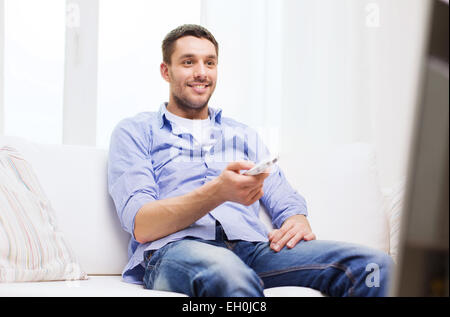 smiling man with tv remote control at home Stock Photo
