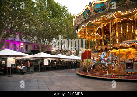 While strollers check out the evening's offerings at the cafes, the carousel adds a touch of fun to the Place de L'Horloge in Stock Photo