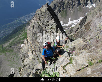 Boy and father rock climbing on a sunny day in the alps.  Mont Blanc is in the backgound. Stock Photo