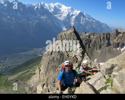 Boy and father rock climbing on a sunny day in the alps.  Mont Blanc is in the backgound. Stock Photo