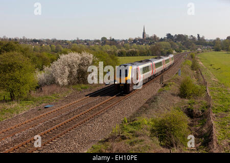 A passenger train approaches past a small village in Oxfordshire, England Stock Photo