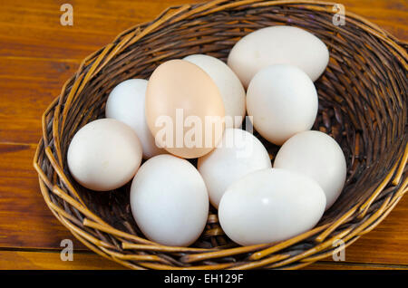 Dozen of white eggs in a wooden basket, placed on a table Stock Photo