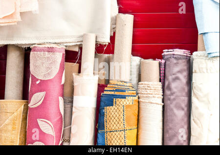 Colorful rolls of patterned fabric on sale at a market Stock Photo