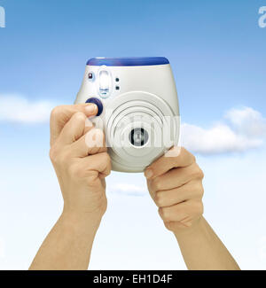 Hand Holding Camera against blue sky. Flashing shot. Clipping path Stock Photo