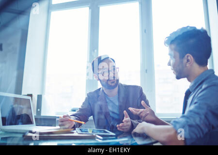 Male colleagues communicating during work Stock Photo
