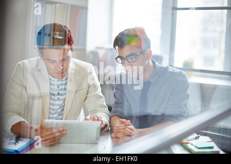 Two young businessmen using digital tablet in office Stock Photo