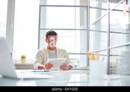 Attractive employee using digital tablet in office Stock Photo
